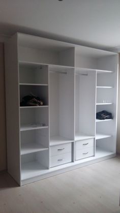 an empty room with white shelves and drawers