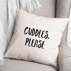 a pillow that says cuddles please on it next to a chair with a blanket