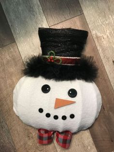 a snowman with a top hat and bow tie on it's head sitting on the floor