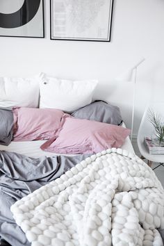 an unmade bed with pillows and blankets on top of it in a white room