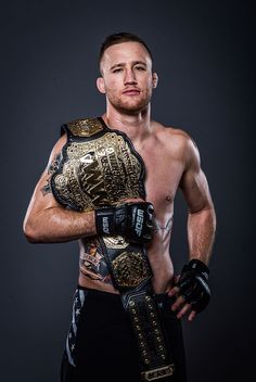 a man in wrestling gear posing for the camera with his hands on his hips and one arm wrapped around him