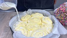 a pan filled with cinnamon rolls next to a bowl of sprinkles