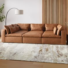 a brown couch sitting on top of a wooden floor next to a white and beige rug