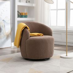 a chair with a yellow blanket on it in front of a window and bookshelf