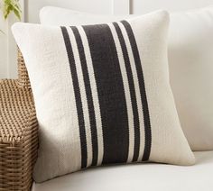 a black and white striped pillow sitting on top of a couch next to a wicker basket