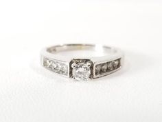 a white gold ring with two diamonds on it's sides and the center diamond in the middle