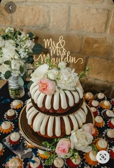 a wedding cake and cupcakes on a table