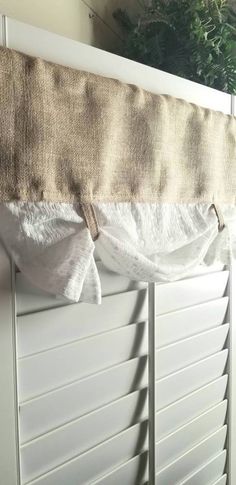 a curtain is hanging on the side of a window sill with shutters open