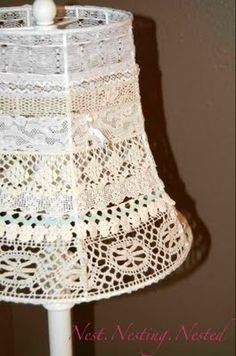 a white lamp shade with crocheted lace on it