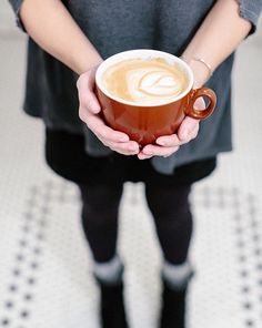 a person holding a cup of coffee in their hands