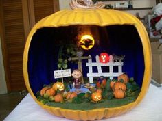 a pumpkin shaped like a house with a little boy inside it on top of a table