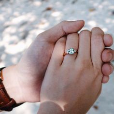 a man and woman holding each other's hand with a diamond ring on their finger