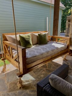 a wooden swing bed with pillows on it