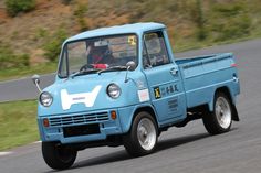 an old blue truck driving down the road