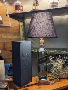 a bottle of whisky sitting on top of a wooden table next to a lamp shade