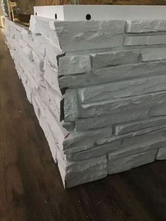 a stack of white bricks sitting on top of a wooden floor next to a wall