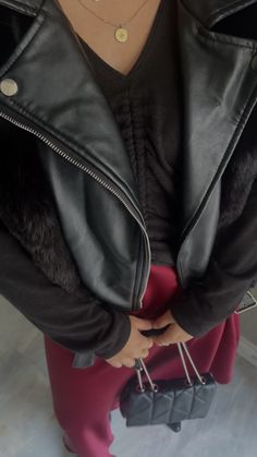 a woman wearing a black leather jacket and pink tights with her hands in her pockets