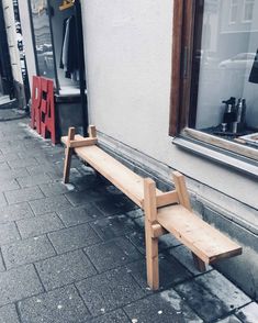 a wooden bench sitting on the side of a street next to a store front window