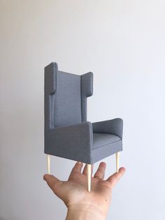 a hand is holding up a miniature chair