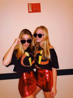 two young women in shiny shorts and black t - shirts are posing for the camera