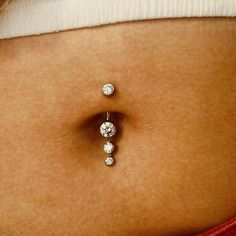 a woman's belly with three diamond studs on the top of her tummy