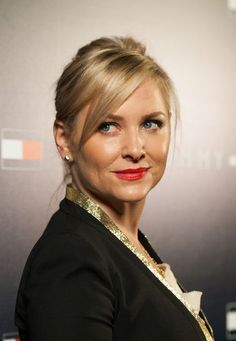 a woman with blonde hair and blue eyes wearing a black blazer posing for the camera