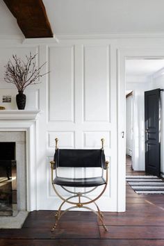 a chair sitting in front of a fire place on a hard wood floor next to a fireplace