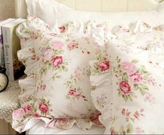 a white bed topped with lots of pillows next to a night stand and alarm clock