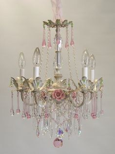 a chandelier hanging from the ceiling with pink flowers and crystal beads on it