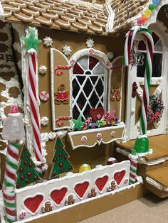 an elaborate gingerbread house with candy canes on the windows and decorations around it