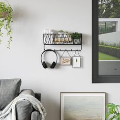 a living room filled with furniture and plants next to a wall mounted art piece on the wall