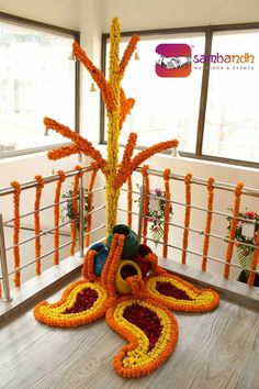 an arrangement of orange and yellow flowers on a wooden table in front of a window