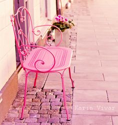 a pink bench sitting on the side of a building next to a flower potted plant