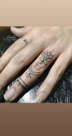 a woman's hand with a flower tattoo on her left thumb and the other finger