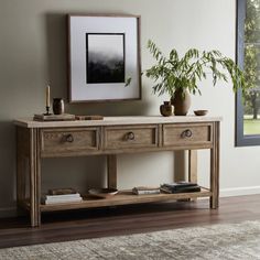 a wooden table with two drawers and a potted plant on it next to a window