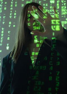 a woman standing in front of a green screen with numbers projected on her face and hands