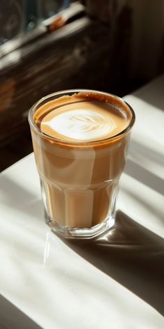 a cup of coffee sitting on top of a table next to a window sill