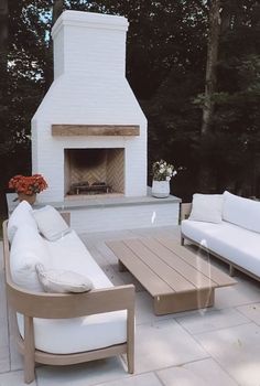 an outdoor living area with white furniture and a fireplace