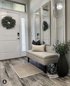 a living room with a couch, mirror and vase on the floor in front of it