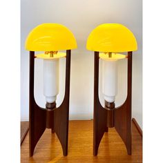 two yellow lamps sitting on top of wooden bases