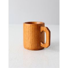 a wooden cup with a handle on a white surface