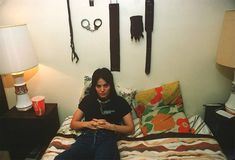 a woman sitting on top of a bed next to a lamp and some keys hanging on the wall