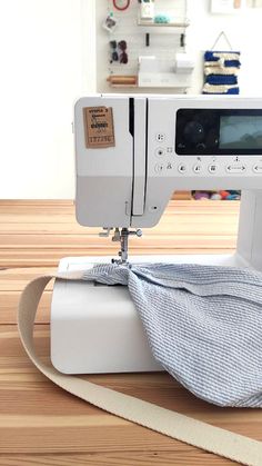 a white sewing machine sitting on top of a wooden table next to a piece of cloth