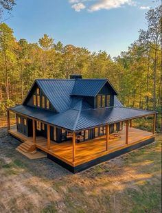 a house in the woods with a metal roof and wooden decking on top of it