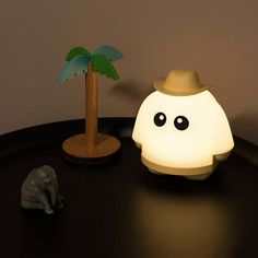 a lamp that is on top of a table next to a toy elephant and palm tree