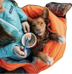 a woman holding a dog in her lap while eating out of a bowl with a spoon