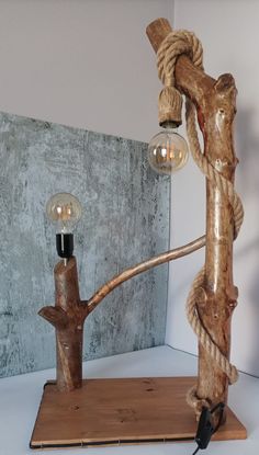 a lamp made out of wood and rope on top of a wooden stand next to a light bulb