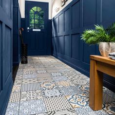 a hallway with blue walls and tile flooring next to a wooden bench in front of a door