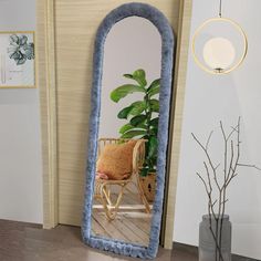 a large mirror sitting on top of a wooden floor next to a potted plant