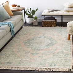 a living room filled with furniture and a rug on top of a wooden floor next to a couch